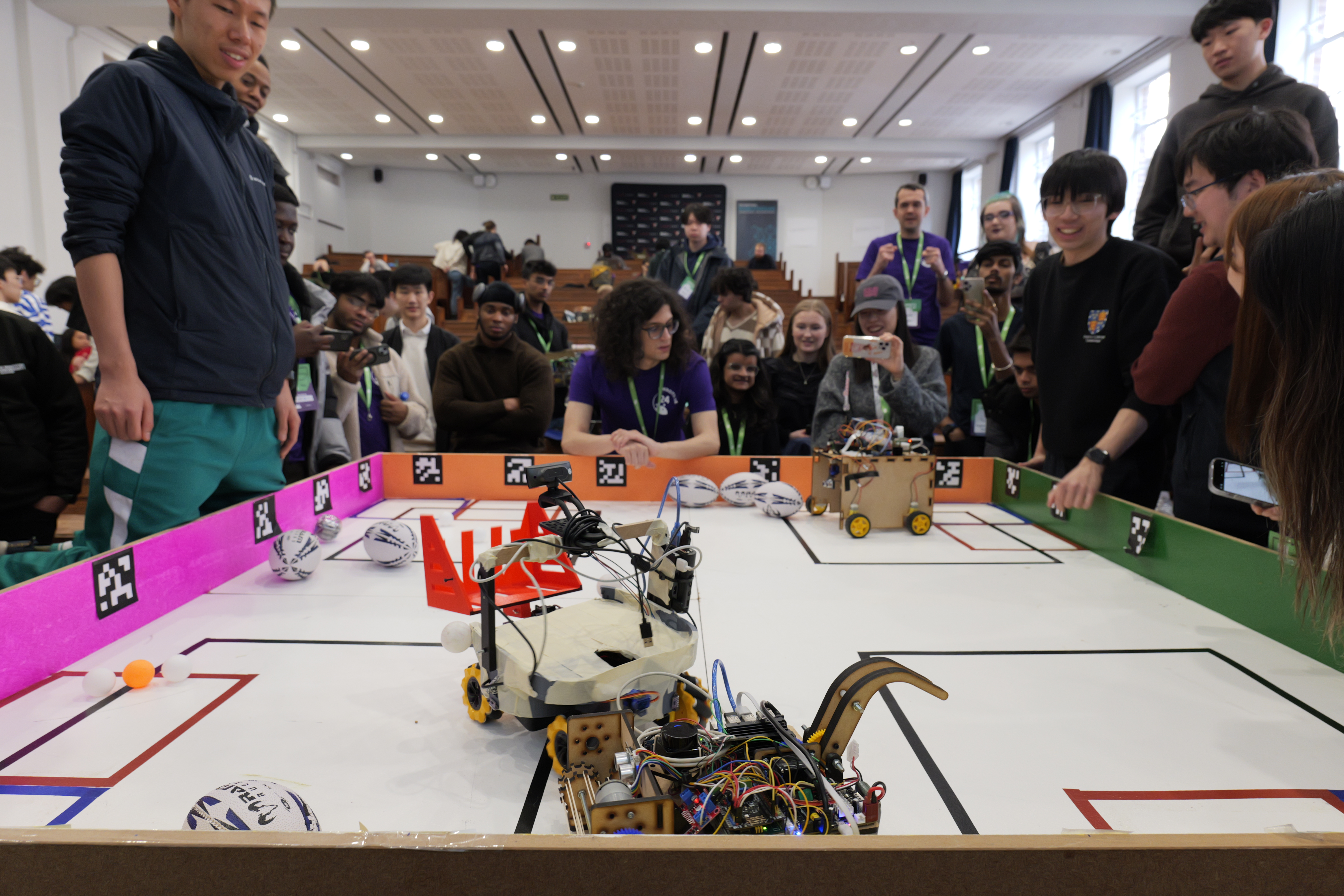 Students gathered around robots competing in the Unibots arena